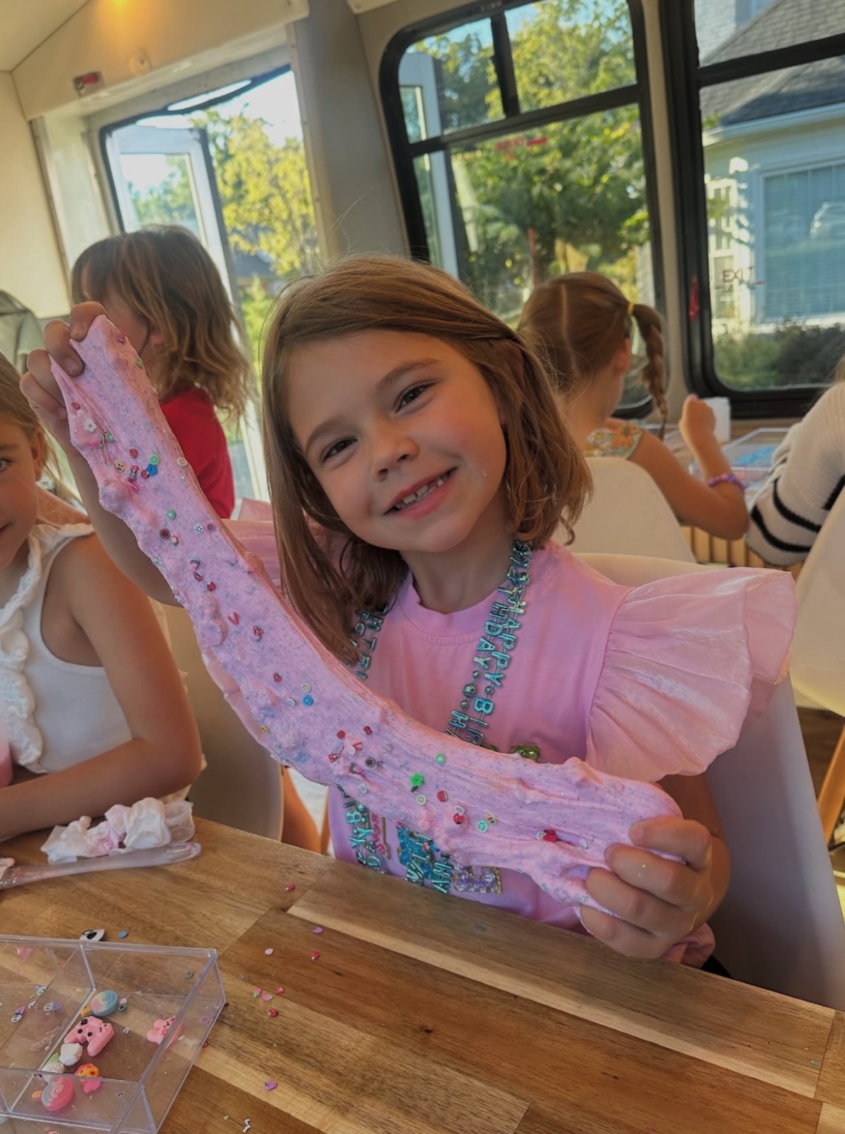 A child joyfully stretching colorful slime at a Kids as Creatives party